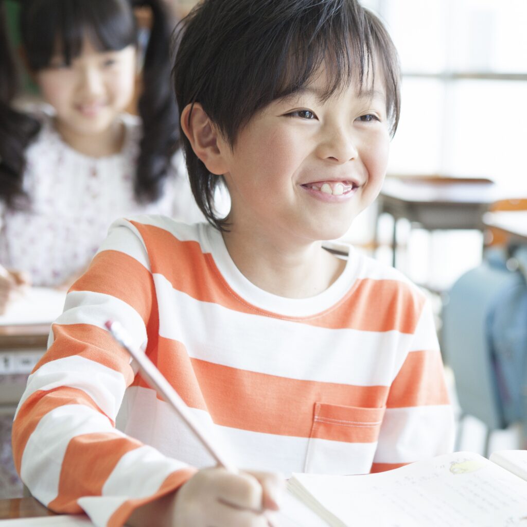 笑顔で鉛筆で字を書く子供